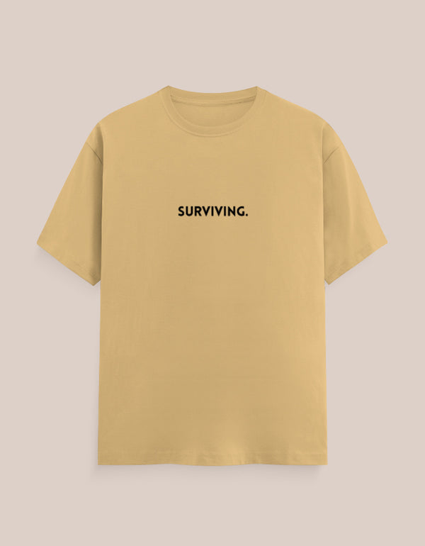 Yellow t-shirt with 'SURVIVING.' text on a beige background