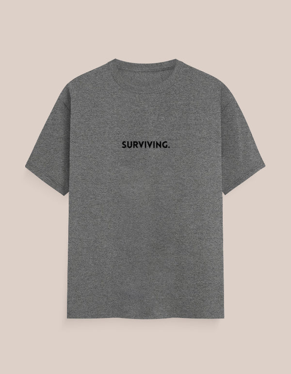 Gray t-shirt with 'SURVIVING.' text on a beige background